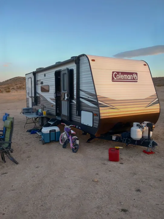 Coleman RV rental readied for desert boondocking, complete with chairs, cooler, and a child's bike for outdoor fun.. Dutchmen Coleman Lantern 2021