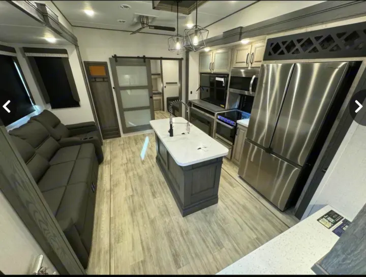 Explore this luxurious RV rental interior featuring a modern kitchen island, stainless steel appliances, and cozy living space.. Keystone Alpine Avalanche 2024