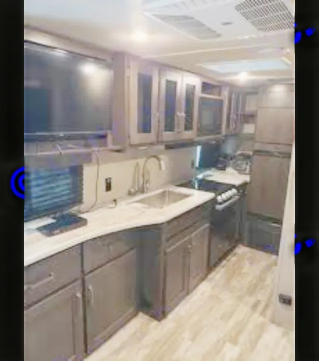 RV rental's modern kitchen & living area with TV, dark cabinets, and appliances for comfortable travel.. Grand Design Transcend Xplor 2021