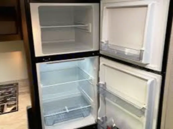 Empty refrigerator and freezer in an RV rental, ready for your travel essentials.. Grand Design Transcend Xplor 2021