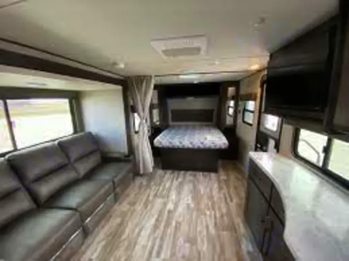Spacious, modern RV interior with living area, kitchen counter, and bedroom. Perfect for your next comfortable RV rental travel.. Grand Design Transcend Xplor 2021