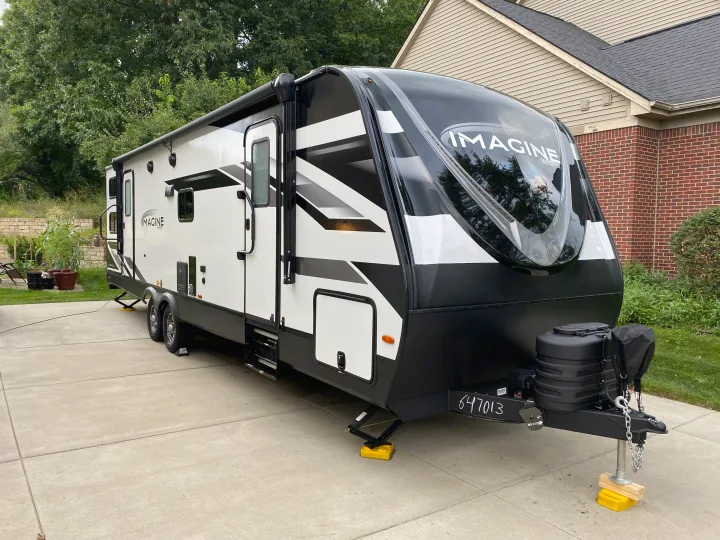 Modern Grand Design Imagine travel trailer, ideal for RV rental, parked on a concrete driveway.. Grand Design Imagine 2023