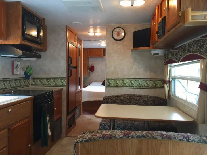 Inside an RV rental: full kitchen, dining booth, and cozy bedroom for comfortable adventures.. Keystone RV Springdale 2005