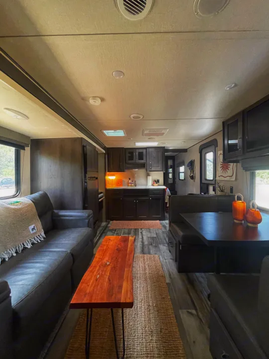 Spacious & modern RV rental interior featuring cozy living area with couch, full kitchen, and dining booth. Ready for adventure!. Grand Design Transcend Xplor 2023