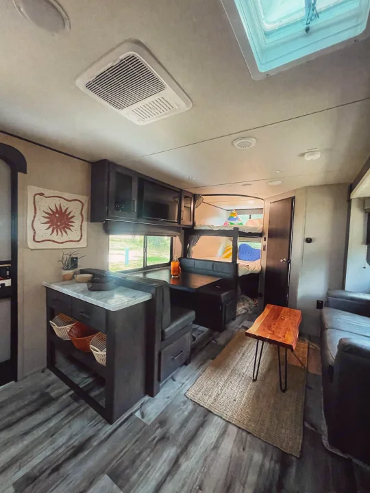 Spacious, modern RV rental interior featuring a kitchen counter, dining area, and cozy bunk beds.. Grand Design Transcend Xplor 2023