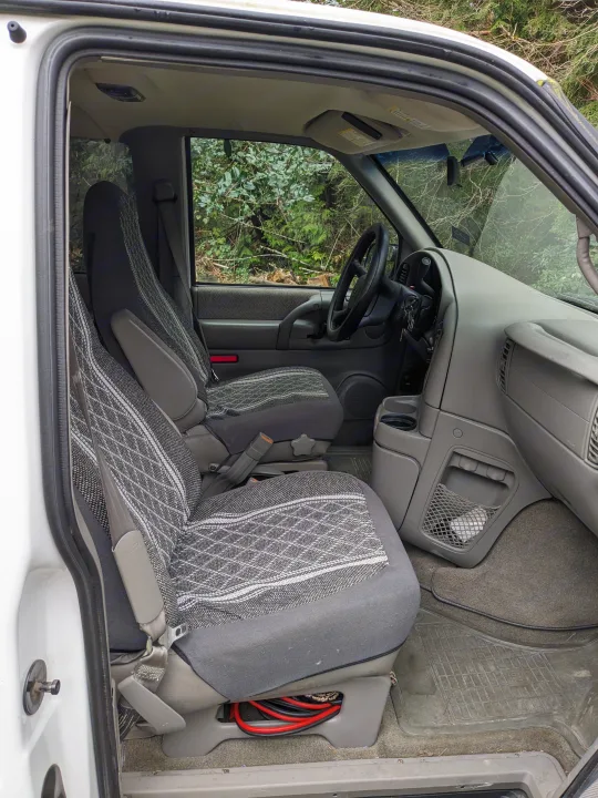 Step inside this RV rental candidate van. View of front cabin, driver/passenger seats, dashboard, and natural scenery.. Chevrolet Open Road 2002