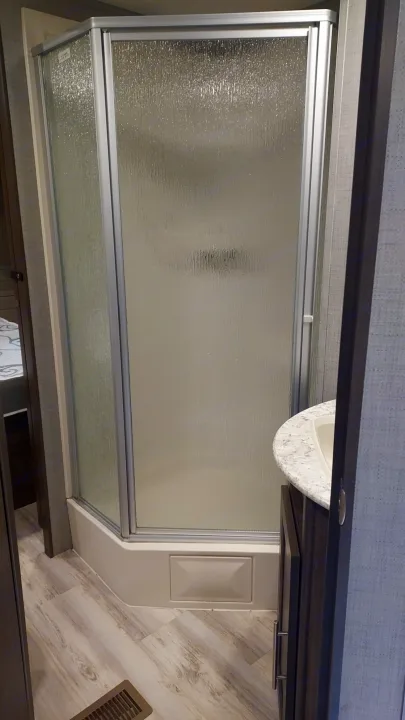 RV rental bathroom features a compact shower with frosted glass doors, a built-in base, and a small vanity.. Crossroads RV Zinger 2018