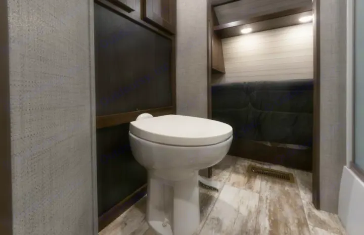 Explore the comfortable interior of an RV rental, featuring a clean toilet in a compact bathroom adjacent to a cozy living area.. Crossroads RV Zinger 2018