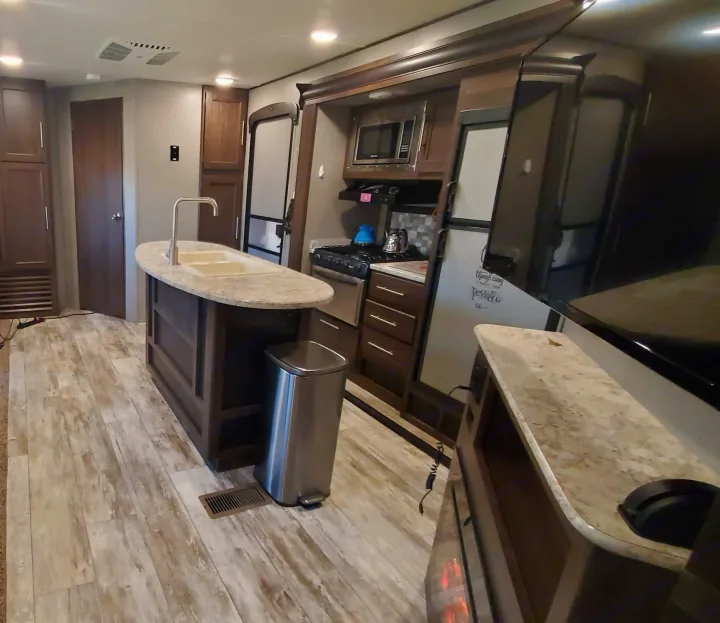 Spacious RV rental interior with kitchen island, modern appliances, and light wood flooring.. Crossroads RV Zinger 2018