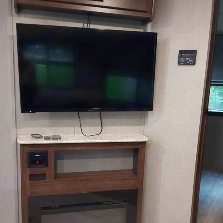 Inside an RV rental: modern entertainment setup with a TV, media console, and thermostat on textured walls.. Crossroads RV Zinger 2018
