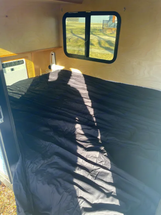 Cozy RV rental interior featuring a comfortable bed, AC unit, and a window with an outdoor view.. County Outbound Extreme 2021