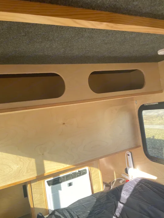 Cozy rv rental interior with light wood paneling, overhead storage, a side window, and a built-in AC unit.. County Outbound Extreme 2021