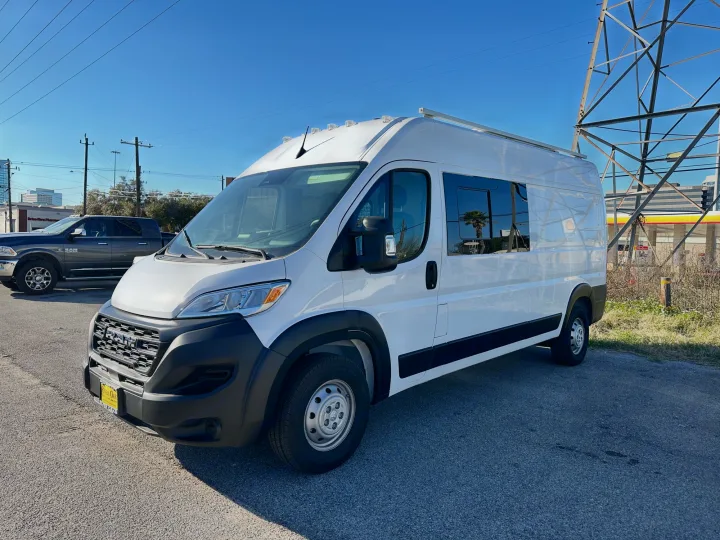 A large, white Ram ProMaster van (likely an rv rental) is parked on asphalt under a clear blue sky.. RAM PROMASTER 2500 2023