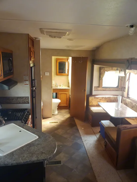 Step inside this RV rental: a practical interior with a kitchen, dining booth, and bathroom. Ready for your travels!. Keystone RV Springdale 2013