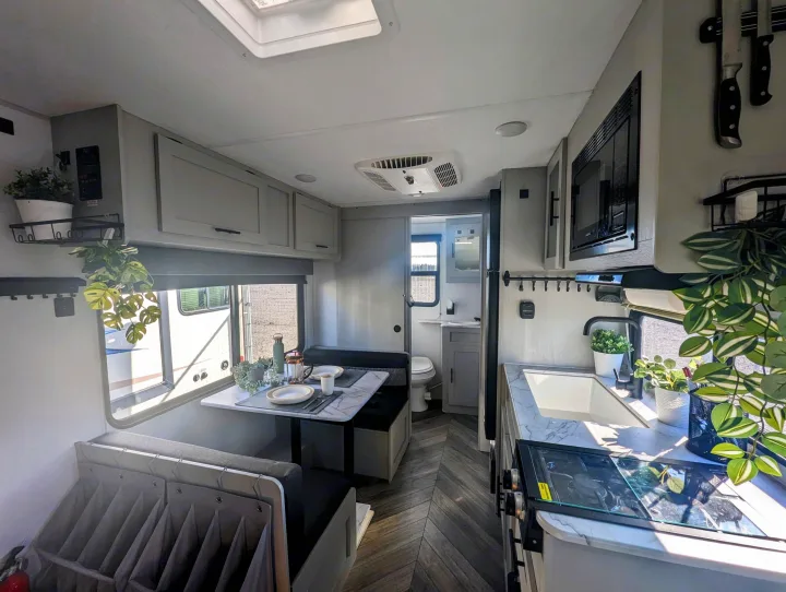 Modern RV rental interior featuring a compact kitchen, dinette, and bathroom, ideal for comfortable travel.. Forest River Wildwood FSX 2021