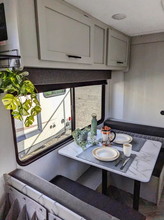 Modern RV rental dining booth, featuring a marble-top table, ready for a cozy meal with coffee.. Forest River Wildwood FSX 2021