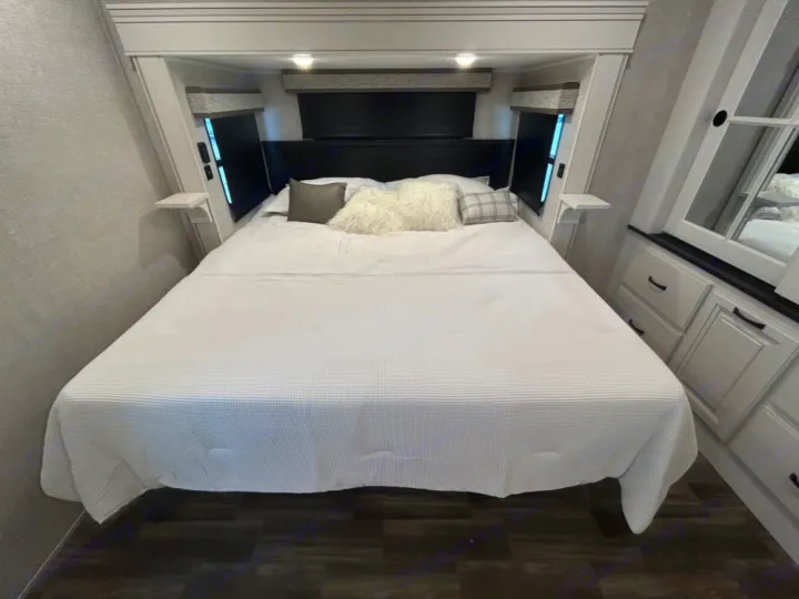 Spacious RV rental bedroom with a large white bed, integrated storage, and soft overhead lighting.. Keystone RV Jayco northpoint 2026