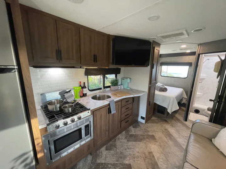 Explore the modern interior of this RV rental, showcasing a functional kitchen, cozy bedroom, and spacious shower.. Forest River Forester 2020