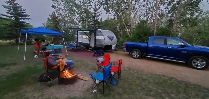 Outdoor movie night with an RV rental! Campers gather around a cozy campfire, enjoying a film projected on the RV at dusk.. Forest River Salem FSX 2019