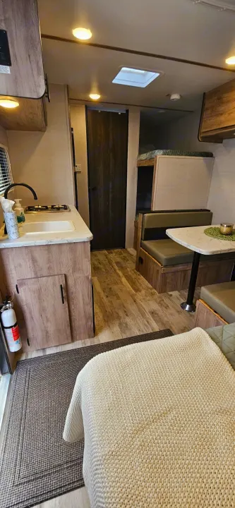 Detailed view of an RV rental interior, showing a kitchen, dinette, bunk beds, and wood-patterned floor.. Gulf Stream Ameri-Lite LE 2023
