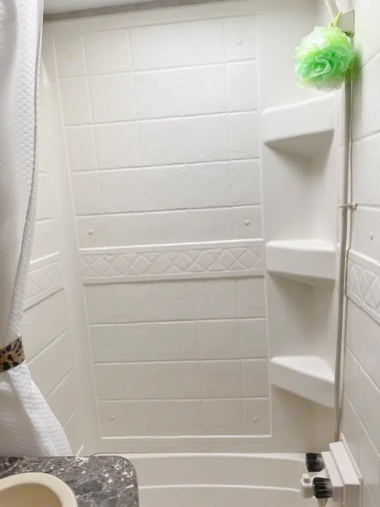 Compact shower and tub in an RV rental, featuring built-in shelves and a tiled look. Ideal for your next adventure.. Keystone RV Passport Grand Touring 2015