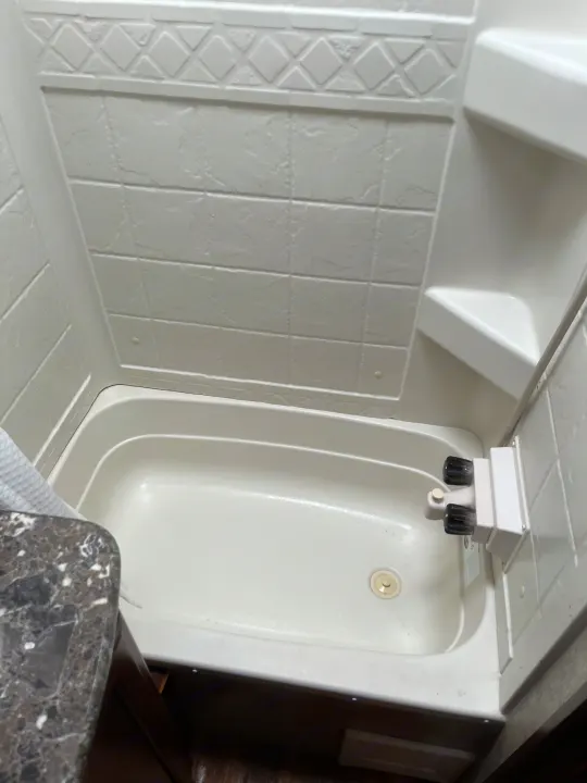 RV rental bathroom interior: a compact white shower and tub unit with textured walls, drain, and faucet controls.. Keystone RV Passport Grand Touring 2015
