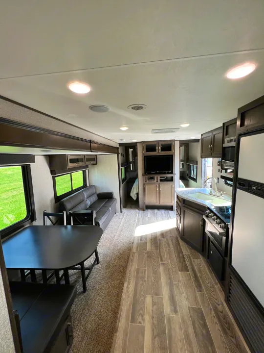 Inside an RV rental: a well-appointed kitchen, dining area, and comfortable living space with a sofa.. Jayco Jay Flight SLX 2021