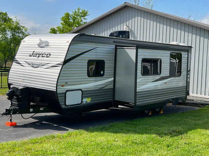 Get ready for your next adventure with this Jayco travel trailer rv rental, parked on asphalt beside a metal building.. Jayco Jay Flight SLX 2021