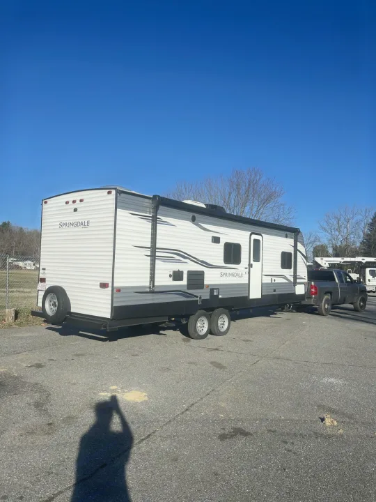 A white Springdale travel trailer is hooked to a pickup truck, ready for your next RV rental adventure.. Keystone RV Springdale 2020