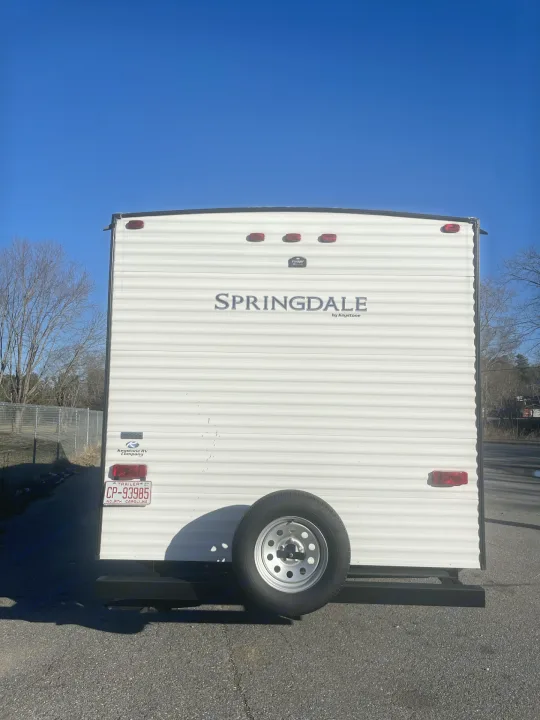 Rear of a white Springdale travel trailer with a spare tire. Great for an RV rental or a camping trip!. Keystone RV Springdale 2020