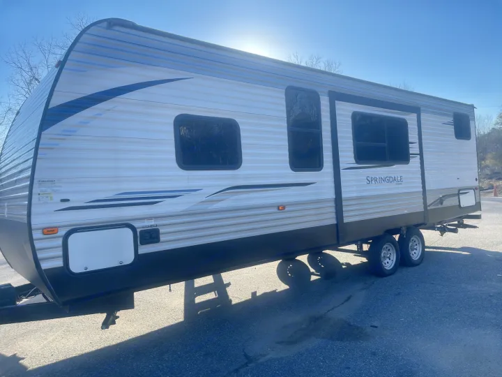 Side view of a bright Springdale travel trailer, ideal for an RV rental. Features windows, door, and dual axles.. Keystone RV Springdale 2020