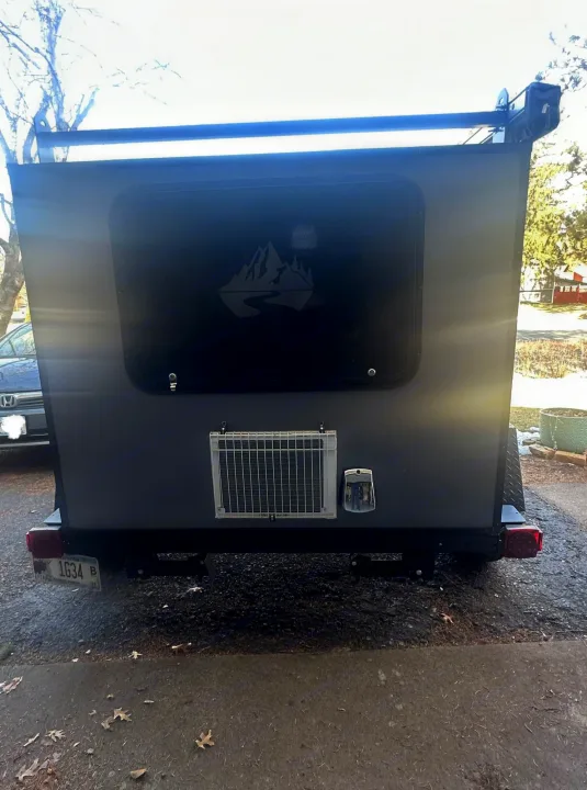 Rear view of a grey teardrop camper, perfect for RV rental adventures. Features a mountain logo on the back window.. Outbound Extreme 2021