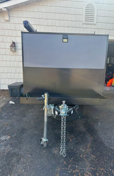 Rugged gray & black enclosed trailer for RV rental, featuring diamond plate, solar light, and front hitch.. Outbound Extreme 2021