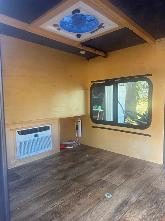 Clean RV rental interior: wood walls, AC, ceiling fan, and window. Ready for your comfortable travels.. Outbound Extreme 2021