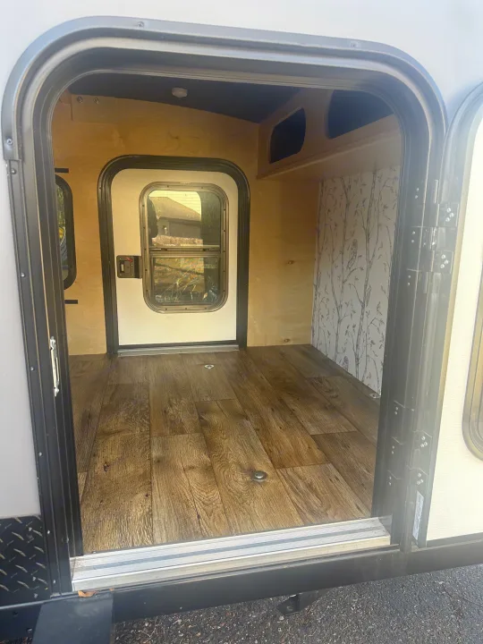 Step inside this cozy rv rental! Features wood-look flooring, natural wood walls, and a whimsical forest wallpaper accent. Perfect for your next adventure.. Outbound Extreme 2021