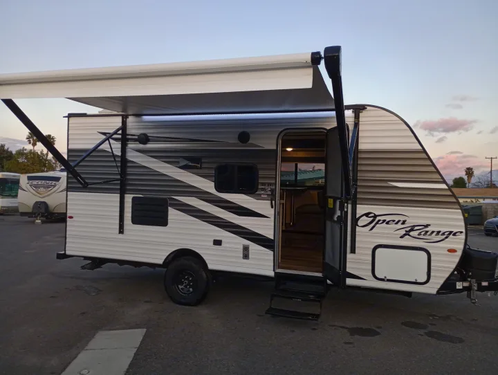 Modern Open Range travel trailer with awning extended and door open, showcasing a great RV rental option.. Highland Ridge RV Open Range 2022