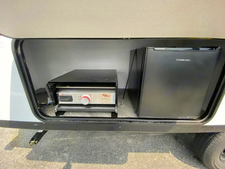 An RV rental's outdoor kitchen with a pull-out Elite griddle and Ever Chill mini-fridge for convenient cooking.. Wildwood FSX 2021