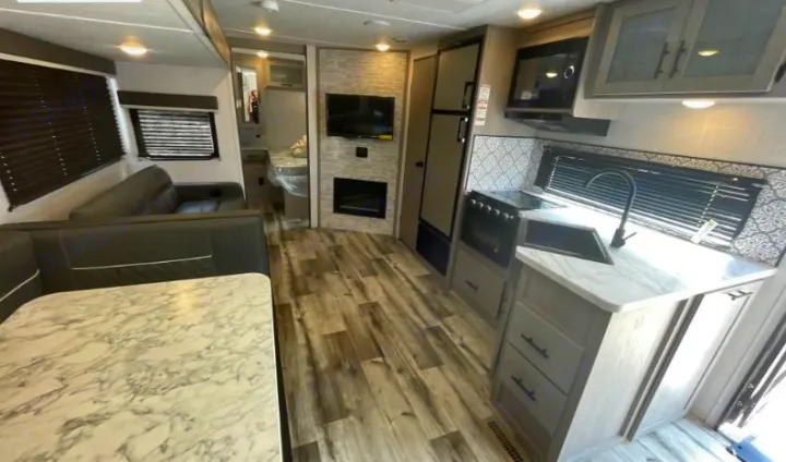 Explore this modern RV rental: a kitchen with oven & microwave, dinette with seating, living area with TV/fireplace, and wood-look floors.. Dutchmen Coleman Light 2023