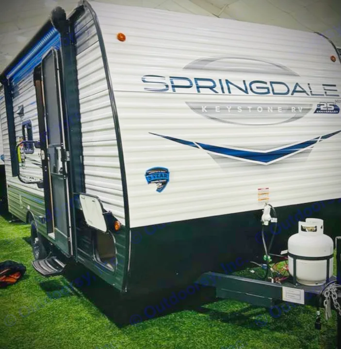 White Springdale Keystone RV travel trailer with black lower section, open door, and front propane tank, for rv rental.. Keystone RV Springdale Mini 1800BH 2024
