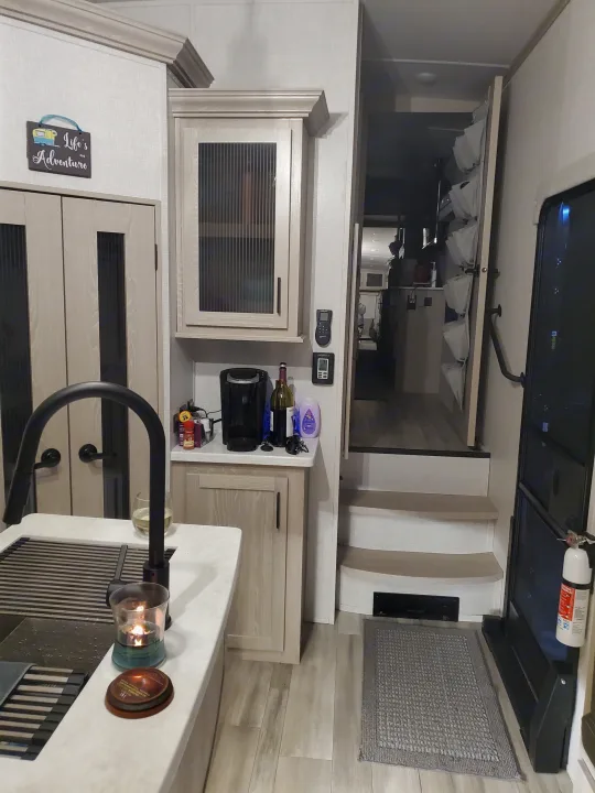 Cozy RV rental interior with a kitchen counter, sink, storage, and steps leading to the main entrance area.. Forest River Rockwood Ultra Lite 2022