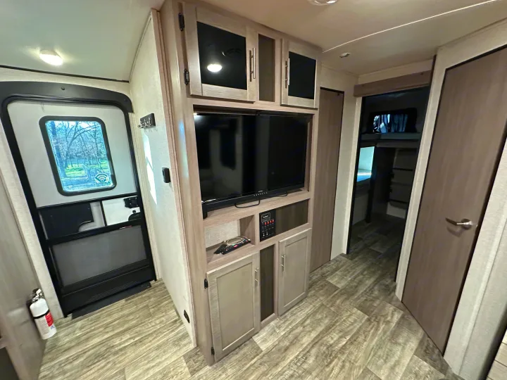 Step inside this RV rental! Modern interior with wood-look flooring, entertainment unit, main door, and bunk beds.. Crossroads RV Sunset Trail 2022