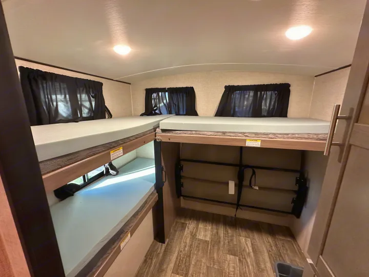 RV rental bunkhouse: A view of multiple bunk beds with foam mattresses and privacy curtains, perfect for group sleeping.. Crossroads RV Sunset Trail 2022