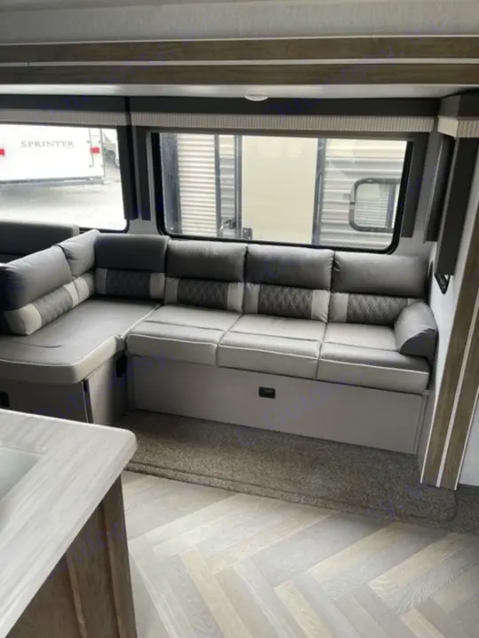 Modern RV rental interior with a comfy L-shaped gray sectional sofa and stylish herringbone flooring.. salem 29VBUD 2022