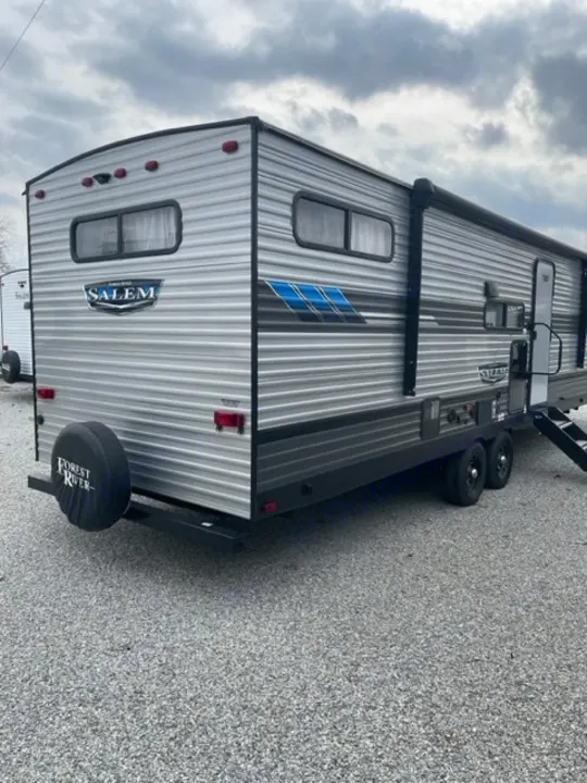 Spacious grey travel trailer with blue accents and an awning, ideal for your next RV rental adventure. Parked on gravel.. salem 29VBUD 2022