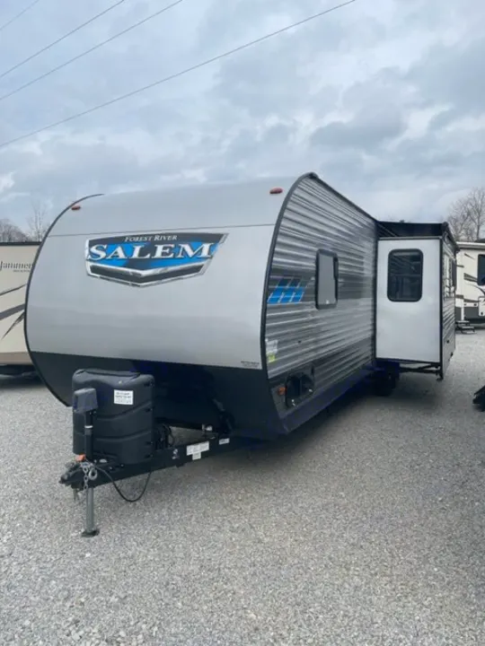 This silver Forest River Salem travel trailer, an excellent option for RV rental and camping adventures, is parked on gravel.. salem 29VBUD 2022