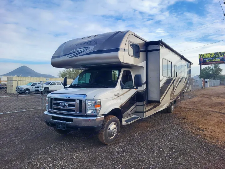 White & gray Forester Class C motorhome rv rental on a Ford chassis, parked on a gravel lot. Ready for adventure.. Forest River forester 2016