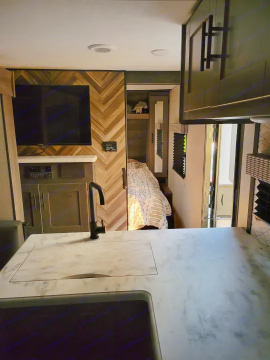 Inside a comfortable rv rental: modern kitchen with sink, cozy living area with TV, and a private bunk bed.. KZ Confluence 2022