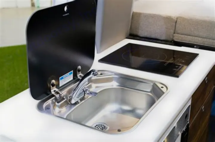 Visually impaired users: A compact RV rental kitchen features a Dometic sink with a flip-up cover and an electric cooktop.. Storyteller Overland Storyteller Overland Class B 2020