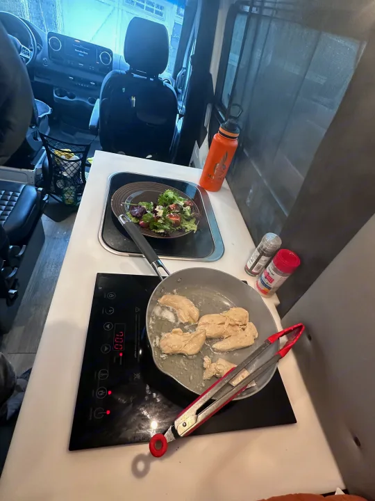 Cooking fresh chicken and salad inside a Mercedes-Benz rv rental. A glimpse of mobile kitchen life.. Storyteller Overland Storyteller Overland Class B 2020