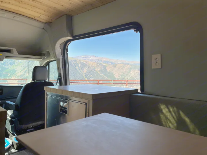 Experience van life! This RV rental offers stunning mountain views from its custom interior, featuring a fridge and cozy seating.. Ford Transit 2022